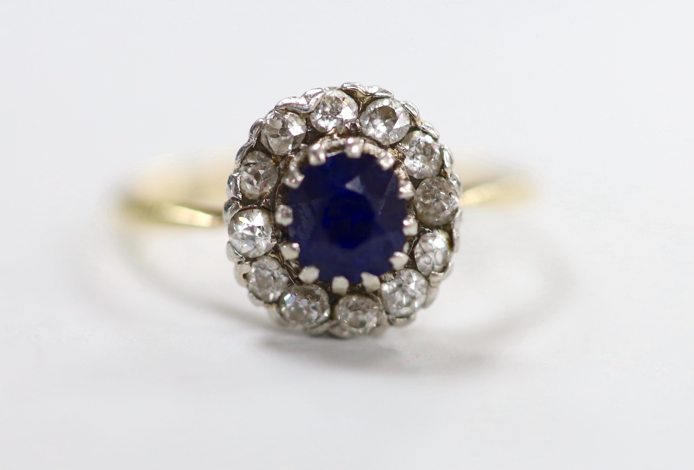 A yellow metal, sapphire and diamond set oval cluster ring, size Q, gross weight 2.8 grams.
